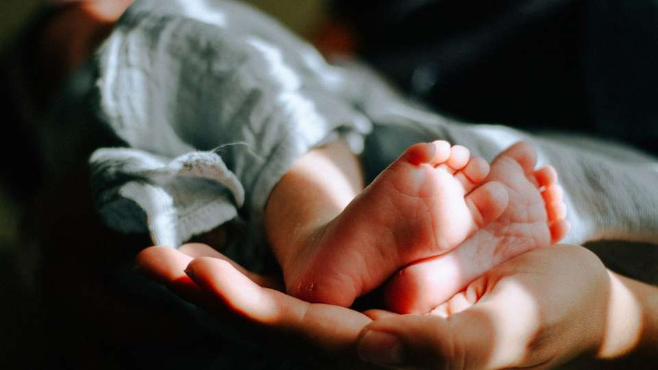 A parent's hands holding a newborn baby's feet