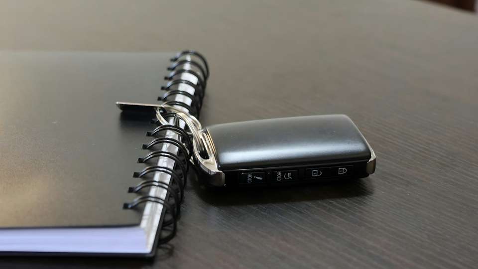 A car key lying next to a spiral notebook on a desk