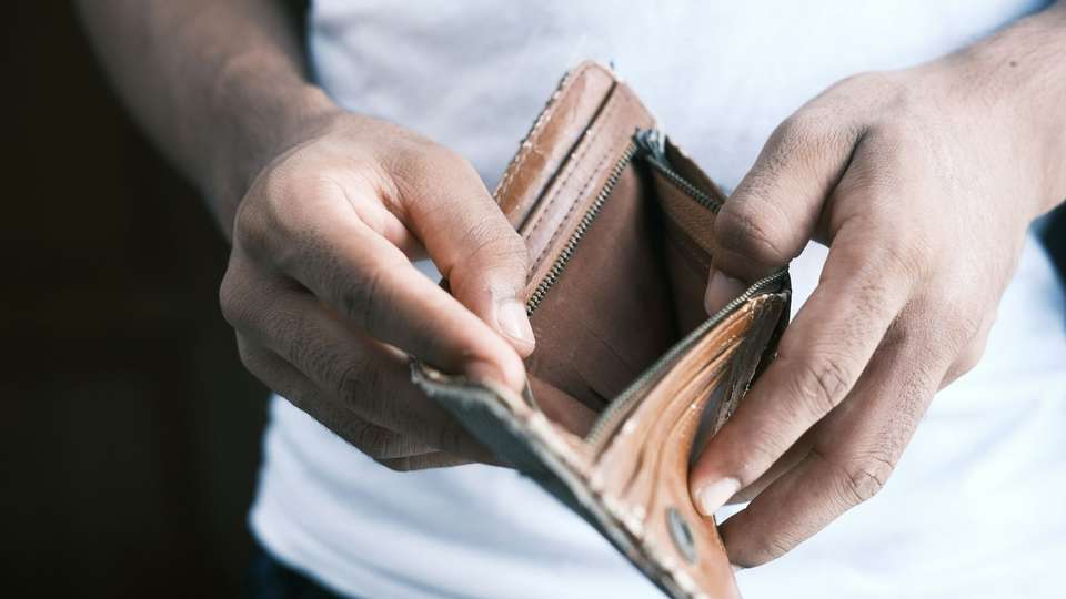 Two hands holding open an empty brown leather wallet