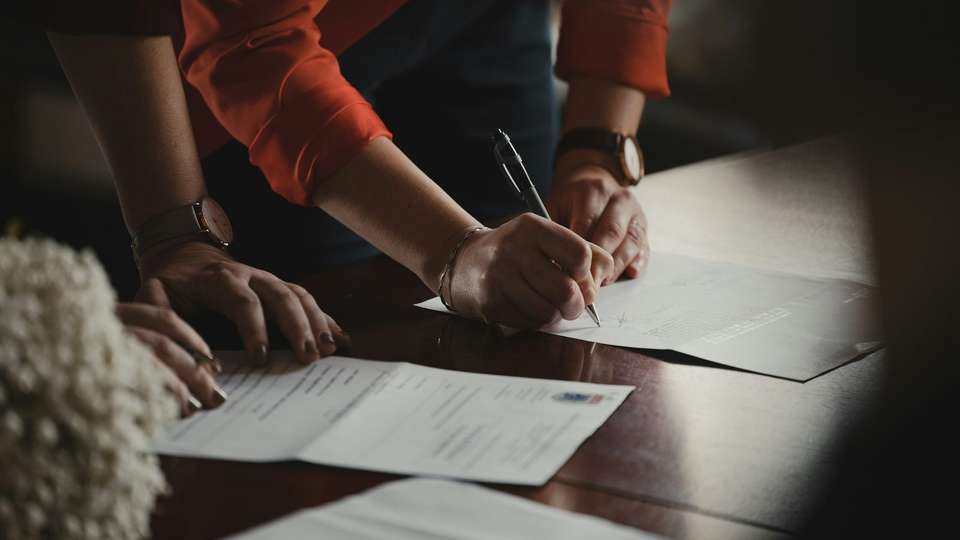 A person filling in a form with a pen at a desk