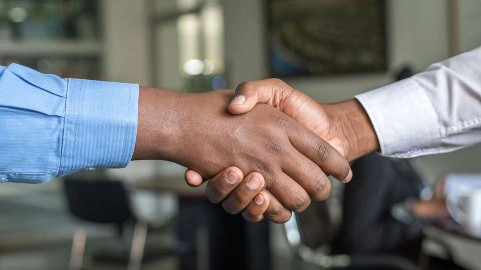 Two people shaking hands across a table in an office