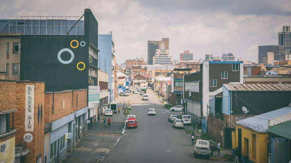 A street of shops and offices in Johannesburg, with cars parked on both sides