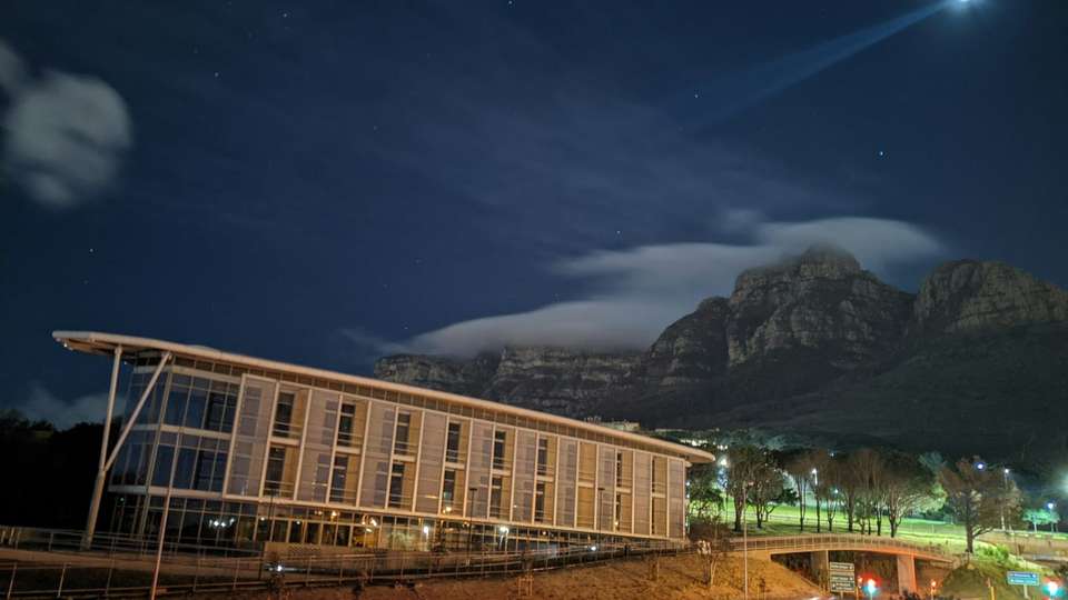 A University of Cape Town building at night, with a mountain behind it