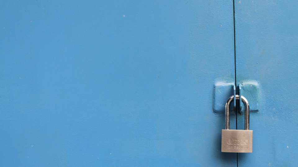 A silver padlock on a blue metal door