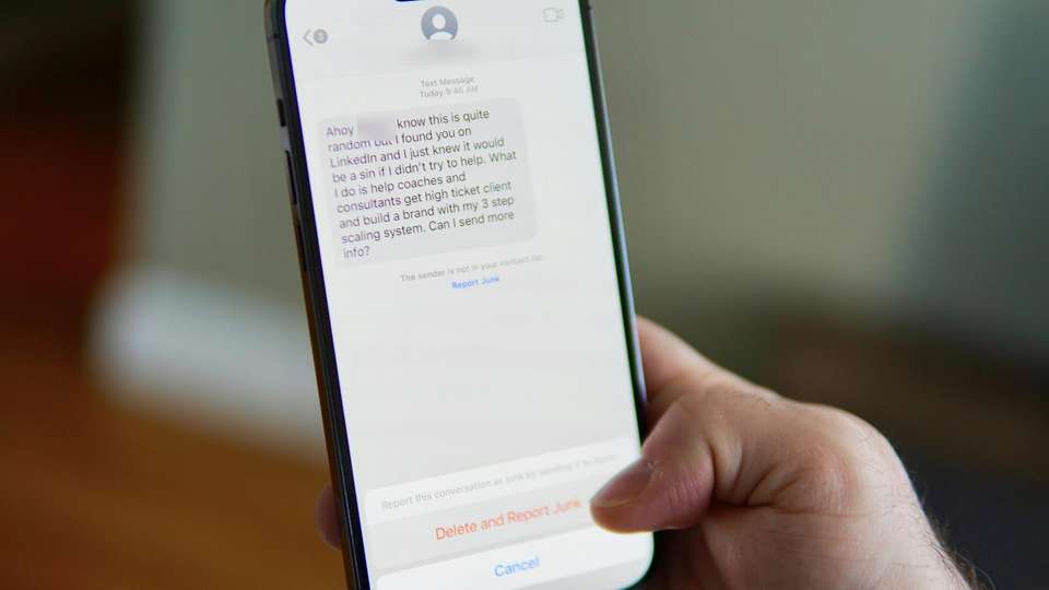 A hand holding a phone that shows a text message from an unknown sender