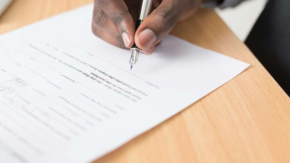 A hand writing with a pen on a printed document
