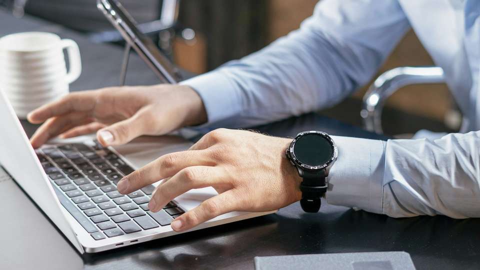 Hands typing on a laptop keyboard at a desk
