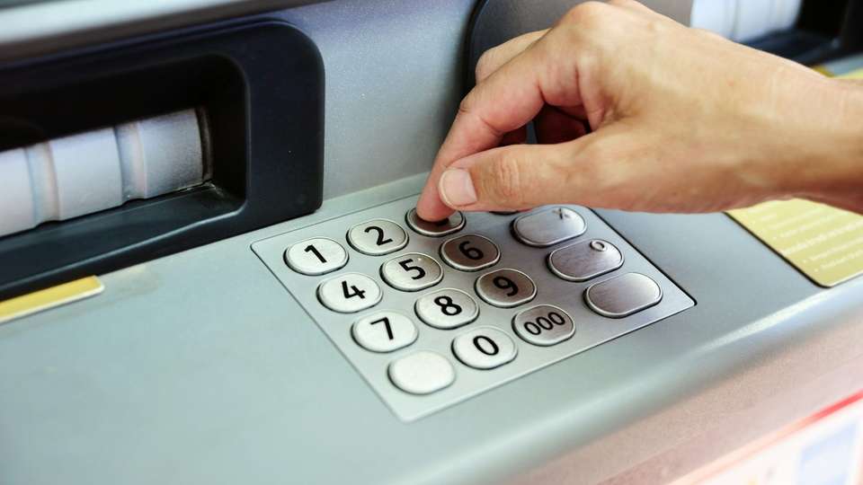 A hand pressing the keypad of a cash machine