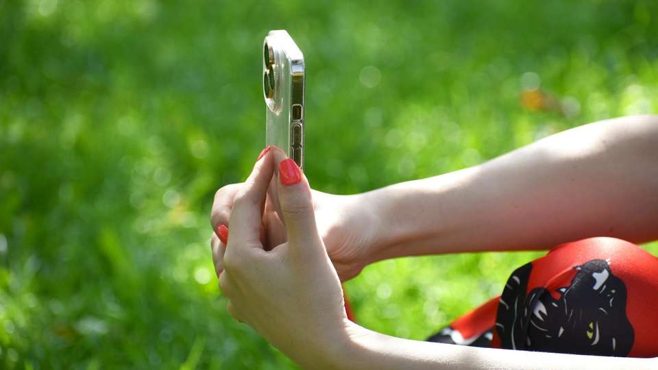 Two hands holding up a smartphone to take a photo outdoors