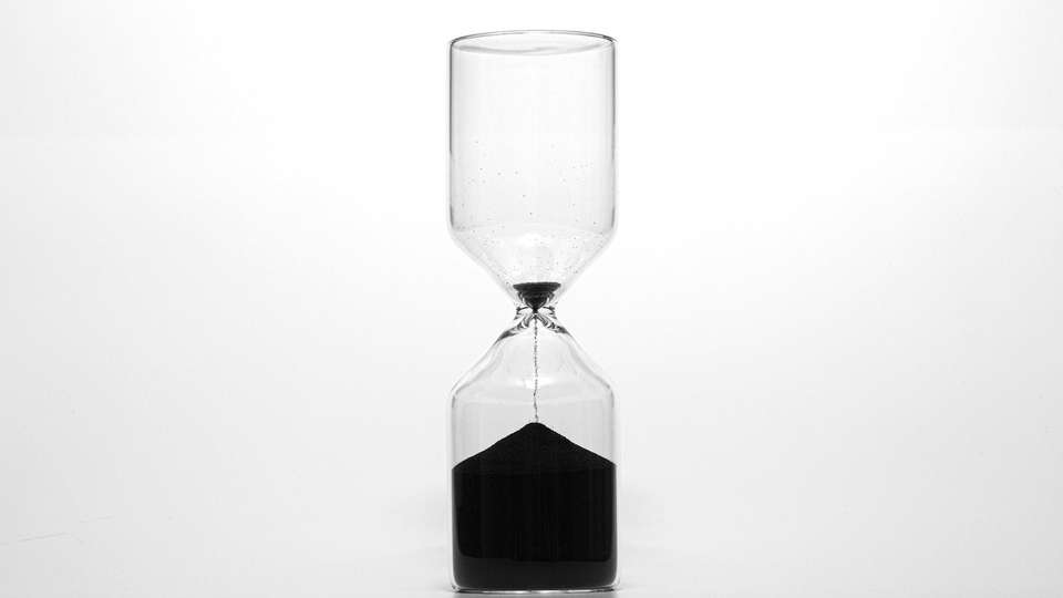An hourglass on a white table with the sand running out