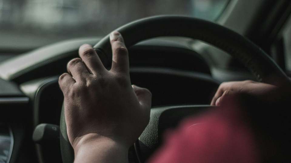 A driver's hand on the steering wheel of a car
