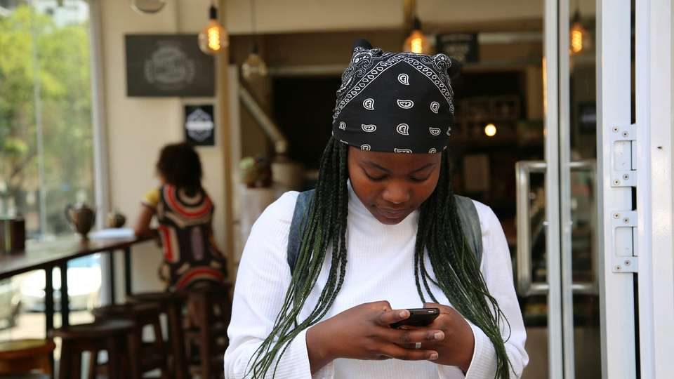 A young woman typing on her phone in a café