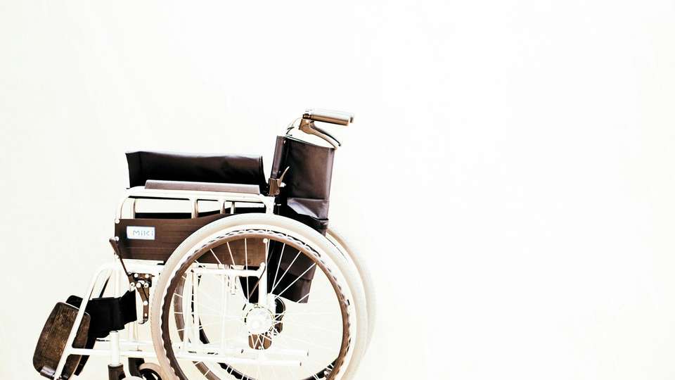 An empty wheelchair against a white wall